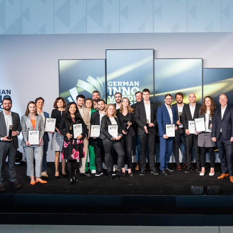 Group of people standing on stage holding awards and certificates at the German Innovation Awards event.