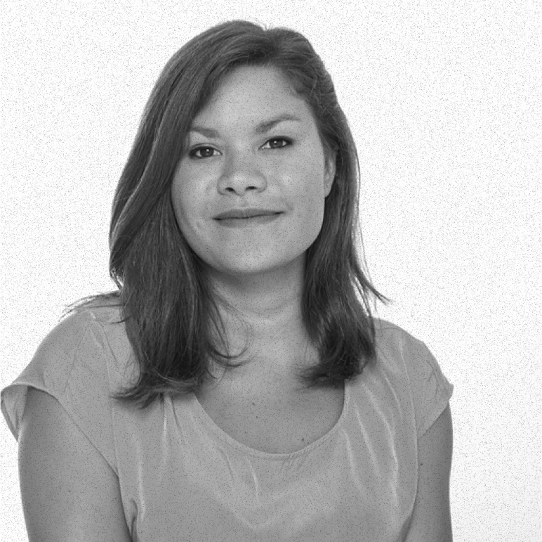 Portrait of a woman with shoulder-length hair wearing a short-sleeve shirt, smiling softly against a plain background.